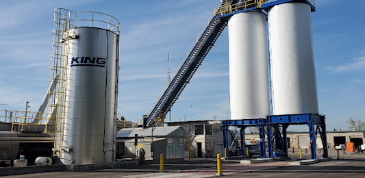 A cement plant with two large silos and a belt.